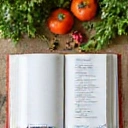 Nyitott receptkönyv és friss alapanyagok egy konyhaasztalon.